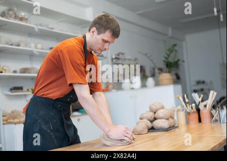 Potter pétrit l'argile avant de l'utiliser dans l'atelier. Banque D'Images