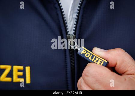 Nuremberg, Allemagne. 22 mai 2024. Le mot « police » est écrit sur la tirette de fermeture éclair et sur la veste d'un policier. Crédit : Daniel Karmann/dpa/Alamy Live News Banque D'Images