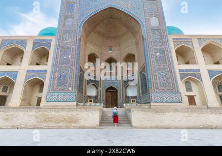 Vue arrière de jeune femme à Boukhara, Ouzbékistan Mir-i-Arab Madrasa Kalyan minaret et tour. Traduction sur la mosquée : 'Mosquée POI Kalyan' Banque D'Images