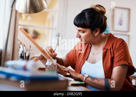 Femme, peinture et artiste avec chevalet en processus de créativité au studio avec inspiration de projet. Peintre, travaillant et croquis avec le pinceau sur cavas dans Banque D'Images