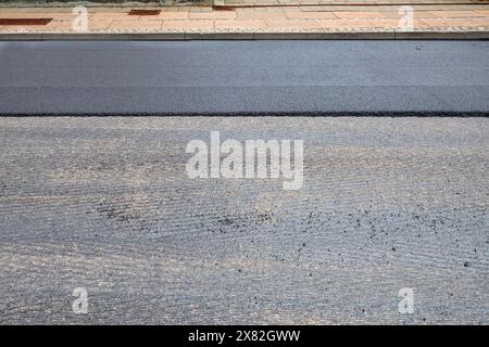 Nouvelle couche d'asphalte et ancien asphalte raclé. Réparation de la surface de la route asphaltée - ancienne couche enlevée et un nouvel asphalte frais sur le chantier de construction. Banque D'Images