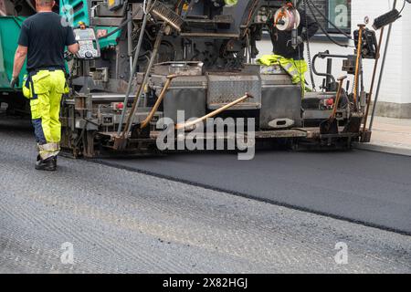 Réparation de la surface de la route d'asphalte - ancienne couche enlevée et un revêtement camion de chaussée industriel posant le nouvel asphalte frais sur le chantier de construction. Banque D'Images