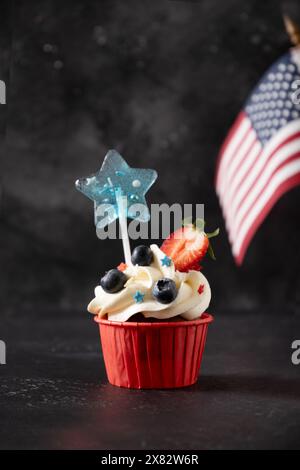 Gâteau sucré à la vanille patriotique américaine décoré de fraises et de bleuets sur fond noir. Bonne journée de l'indépendance. Format vertical. Banque D'Images