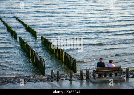 Ein älteres Paar sitzt auf einer Bank am Strand, BEI Flut, Wellenbrecher, Niederlande Senioren *** un couple de personnes âgées est assis sur un banc sur la plage, à marée haute, brise-lames, pays-Bas Seniors Banque D'Images