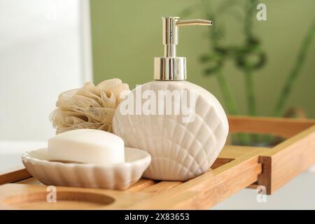 Plateau de bain en bois avec différentes fournitures et produits cosmétiques dans la salle de bains lumineuse Banque D'Images