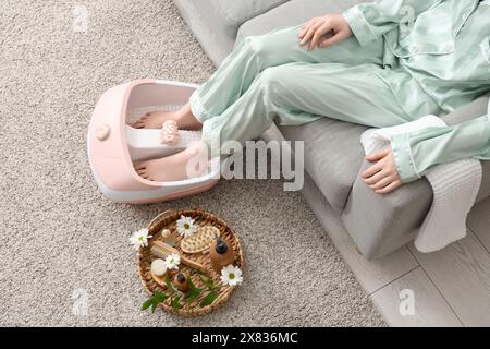 Femme avec des fournitures de spa en utilisant le bain de pied de massage à la maison Banque D'Images