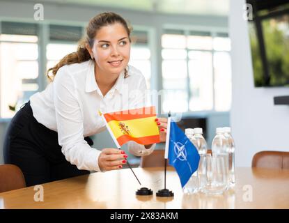 Femme d'affaires qui organise les drapeaux de l'OTAN (OTAN) et de l'Espagne pour la présentation et les négociations Banque D'Images