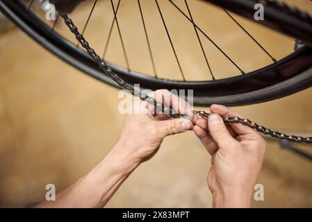 Réparateur travaillant : homme inconnu verrouillant la chaîne d'un vélo dans son atelier de vélo. De vraies personnes au travail. Vue rapprochée des mains. Banque D'Images