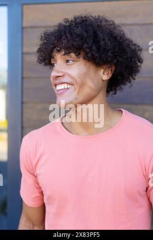 Un jeune homme biracial portant une chemise rose, souriant dehors Banque D'Images