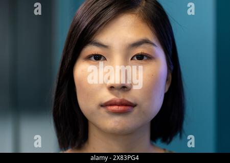 Jeune femme asiatique avec les cheveux noirs courts et la peau lisse debout dans un bureau moderne pour les affaires Banque D'Images