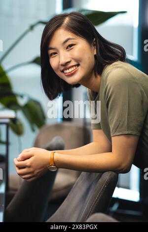 Au bureau moderne pour les affaires, jeune femme asiatique avec les cheveux noirs courts et la peau claire souriante Banque D'Images