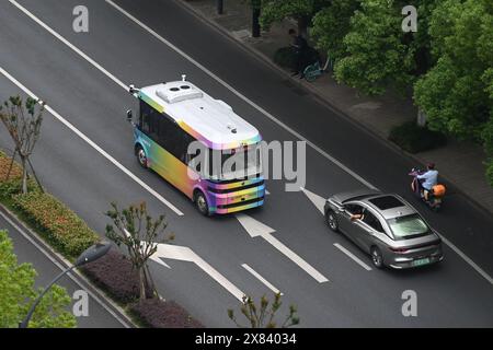 Pékin, province chinoise du Zhejiang. 22 mai 2024. Un minibus à conduite autonome circule sur une route dans le district de Yuhang, ville de Hangzhou, province du Zhejiang de l'est de la Chine, le 22 mai 2024. La ligne de bus de conduite autonome dans le district de Yuhang est la première de son genre alimentée par la technologie de coordination véhicule-route à Hangzhou. Cette ligne de bus de 5 kilomètres serpente à travers les écoles, les parcs industriels, les complexes résidentiels et les stations de métro, gratuitement pour tous les citoyens. Crédit : Huang Zongzhi/Xinhua/Alamy Live News Banque D'Images