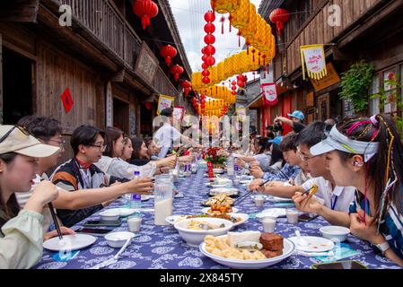 NINGBO, CHINE - 19 MAI 2024 - les touristes goûtent à la nourriture au long banquet de table dans la ville antique de Qiantong à Ningbo, province du Zhejiang, Chine, le 19 mai 202 Banque D'Images