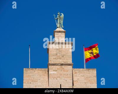 Flèche historique avec statue d'ange et agitant le drapeau espagnol contre le ciel bleu, cathédrale historique dans une ville méditerranéenne contre le ciel bleu, Palma de Banque D'Images