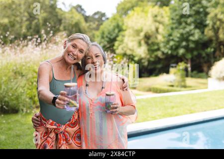 À l'extérieur, diverses amies seniors debout près de la piscine Banque D'Images