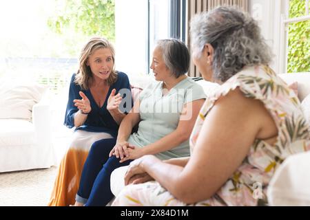 Diverses amies seniors discutant à la maison, se prélassant sur le canapé Banque D'Images