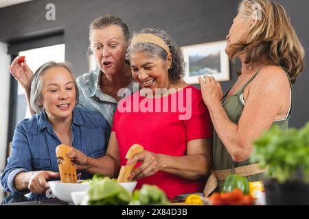 Diverses amies seniors cuisinant ensemble à la maison Banque D'Images