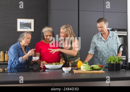 Diverses amies seniors cuisinant ensemble à la maison Banque D'Images