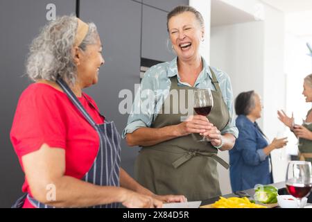 Diverses amies seniors riant, cuisinant à la maison Banque D'Images