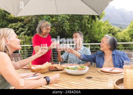 Diverses amies seniors grillant des verres à l'extérieur Banque D'Images