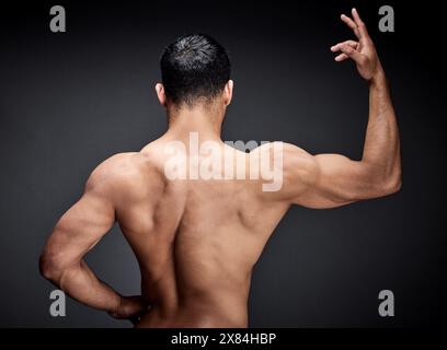 Homme musclé, dos et fitness avec muscle pour la force, l'entraînement ou l'exercice en studio sur un fond noir. Vue arrière de la personne masculine, bodybuilder ou Banque D'Images