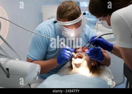 Le médecin scanne les dents du patient à la clinique. Le dentiste tient dans sa main un scanner 3D manuel pour la mâchoire et la bouche. La santé dentaire. Crée des dents et des gencives sur le moniteur médical. Banque D'Images