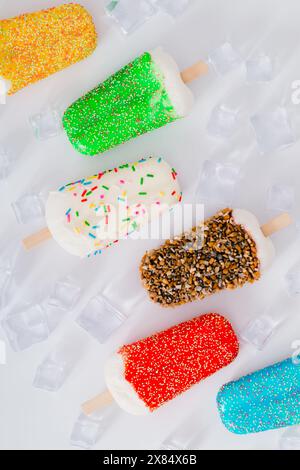 Composition d'été faite avec des popsicles de crème glacée colorées et des glaçons sur fond blanc. Concept estival créatif minimal. Banque D'Images