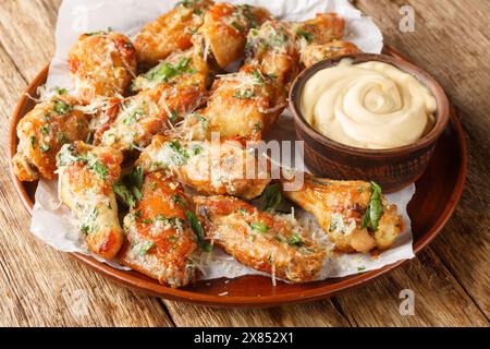 Ailes de poulet au beurre de parmesan à l'ail classiques servies avec mayonnaise en gros plan dans une assiette sur la table. Horizontal Banque D'Images