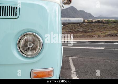 Un bus bleu avec un grand phare est garé sur une route. La route est vide et le ciel est nuageux Banque D'Images