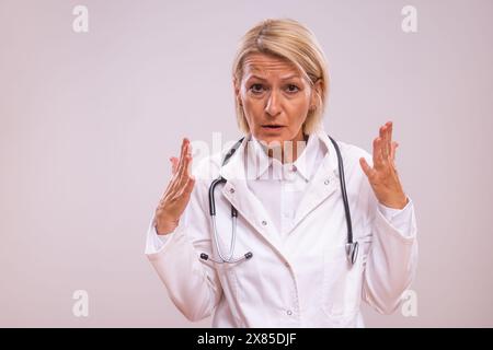 Portrait de médecin féminin mature en colère criant sur fond gris. Banque D'Images