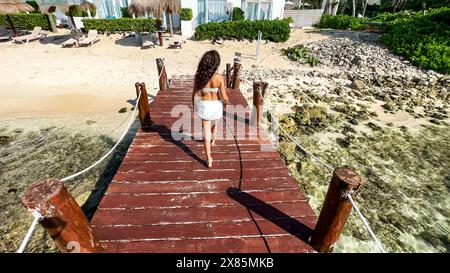 Femme marchant le long de la jetée d'une plage paradisiaque de la Riviera Maya (Mexique), ce quai est sur une eau turquoise cristalline qui mène au W. Banque D'Images