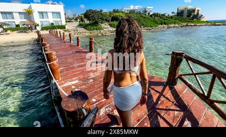 Femme marchant le long de la jetée d'une plage paradisiaque de la Riviera Maya (Mexique), ce quai est sur une eau turquoise cristalline qui mène au W. Banque D'Images