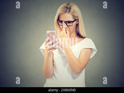 femme portant des lunettes avec des problèmes de vue essayant de lire le texte du téléphone Banque D'Images