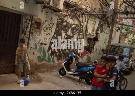 Beyrouth, Liban. 18 mai 2024. Des enfants jouent près d'une murale représentant le défunt dirigeant palestinien Yasser Arafat dans le camp de réfugiés de Bourj el-Brajneh, Beyrouth, Liban, le 18 mai 2024. Environ 25 000 Palestiniens vivent à Bourj el-Brajneh. (Photo de Collin Mayfield/Sipa USA) crédit : Sipa USA/Alamy Live News Banque D'Images