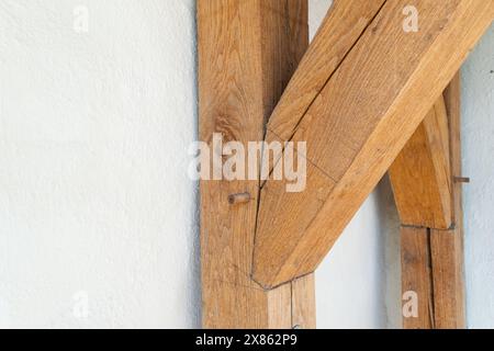 Gros plan de poutres en bois rustiques croisées mettant en valeur la texture et l'artisanat contre un mur blanc. Idéal pour les thèmes de la construction, de l'architecture Banque D'Images