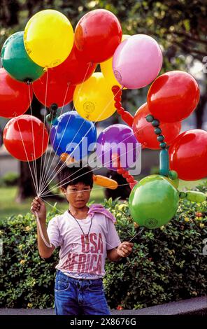 Philippines, Manille ; garçon vendant des ballons dans la rue. Banque D'Images