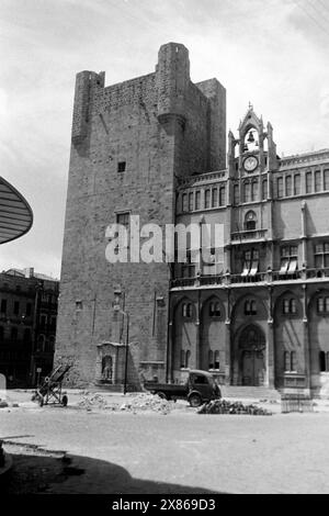 Eine Baustelle befindet sich vor dem ehemaligen Palast der Erzbischöfe von Narbonne, dessen Turm auf der linken Seite romanischen Ursprungs ist, während das weitere Gebäude der katalanischen Gotik zugerechnet wird, Frankreich 1957. Il y a un chantier en face de l'ancien palais des archevêques de Narbonne, dont la tour à gauche est d'origine romane, tandis que le reste du bâtiment est gothique catalan, France 1957. Banque D'Images