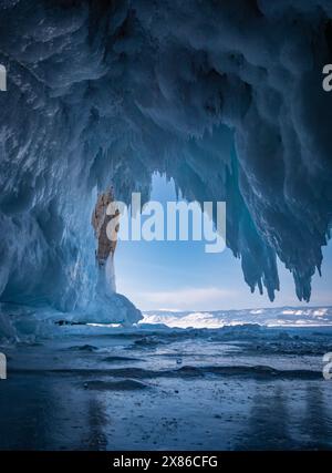 À l'intérieur d'une magnifique grotte de glace sur le lac Baïkal, de grands glaçons pendent du plafond, créant un paysage hivernal à couper le souffle. Les montagnes enneigées peuvent Banque D'Images