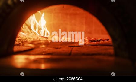 Dans Restaurant Pizza Peel transférer Pizza dans Wood Fire Stone four. Cuisine traditionnelle, recette familiale italienne. Pizzeria authentique avec délicieux aliments biologiques. Cinématographique No People Shoot Banque D'Images