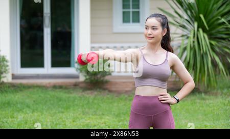 Une femme instructeur de fitness s'entraînant avec une petite haltère sur la cour. Banque D'Images