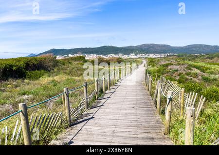 Une promenade en bois à travers les dunes de sable mène à une ville côtière de Vila Praia de Ancora nichée contre les collines Banque D'Images