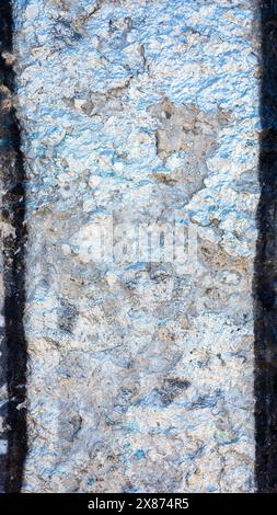 Photo verticale d'un vieux mur fissuré avec des bords noirs qui a été peint avec de la peinture argentée brillante. Banque D'Images