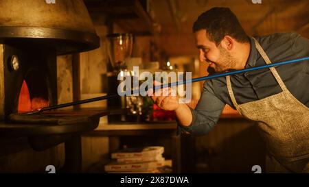 Dans le restaurant, le chef professionnel utilise Pizza Peel pour transférer la pizza dans le four en pierre à feu de bois. Recette familiale de cuisine italienne traditionnelle. Pizzeria authentique, délicieux aliments biologiques. Prise de vue cinématographique Banque D'Images