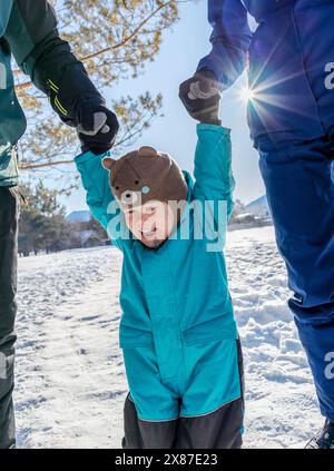 Garçon heureux tenant la main de la mère et du père dans la forêt d'hiver Banque D'Images