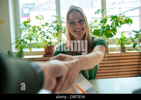 Souriante femme d'affaires mature serrant la main avec homme d'affaires au bureau Banque D'Images