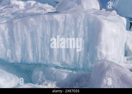 Fond naturel d'hiver avec des fragments de glace bleue et des tas de morceaux de glace sur le lac Baïkal par une journée ensoleillée et glacée. Fond froid abstrait, Banque D'Images