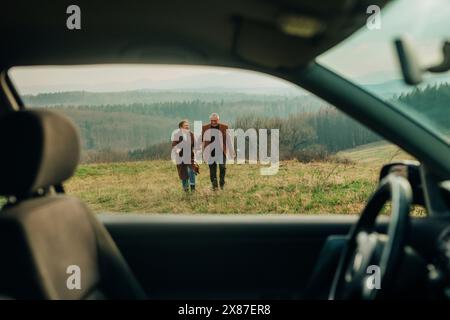 Heureux couple senior profitant de vacances sur la montagne vu à travers la fenêtre de la voiture Banque D'Images