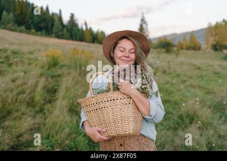 Femme souriante avec les yeux fermés tenant le panier de fleurs Banque D'Images