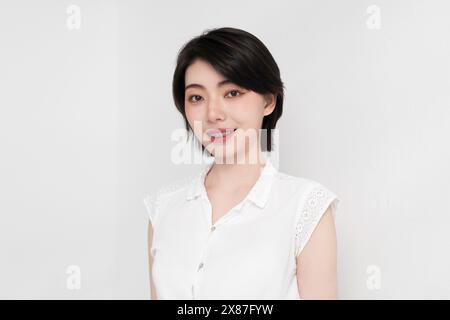 Jeune femme souriante avec des appareils dentaires sur fond blanc Banque D'Images