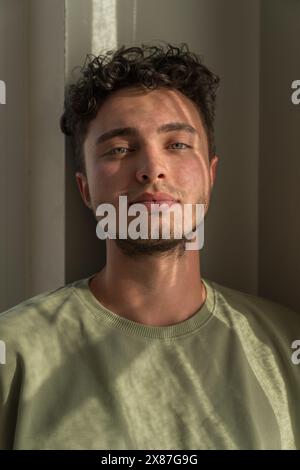 Jeune homme portant un t-shirt vert et appuyé sur le mur Banque D'Images